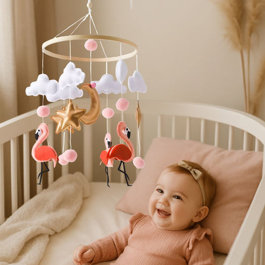 mobile bebe flamant rose fille souriante dans berceau